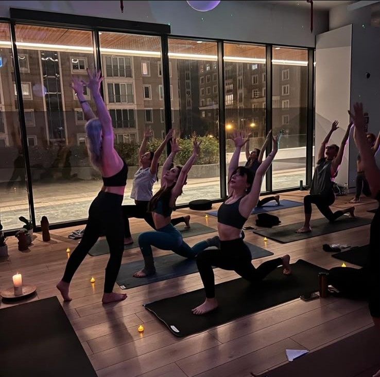 An evening Mirage yoga class in a candlelit studio with floor-to-ceiling windows